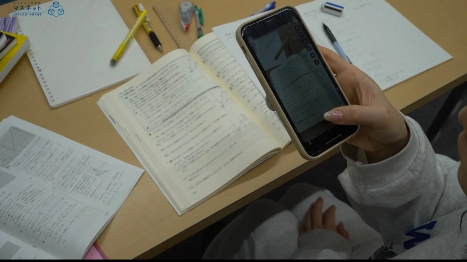 解いた問題のページをスマートフォンで撮影する生徒の手元